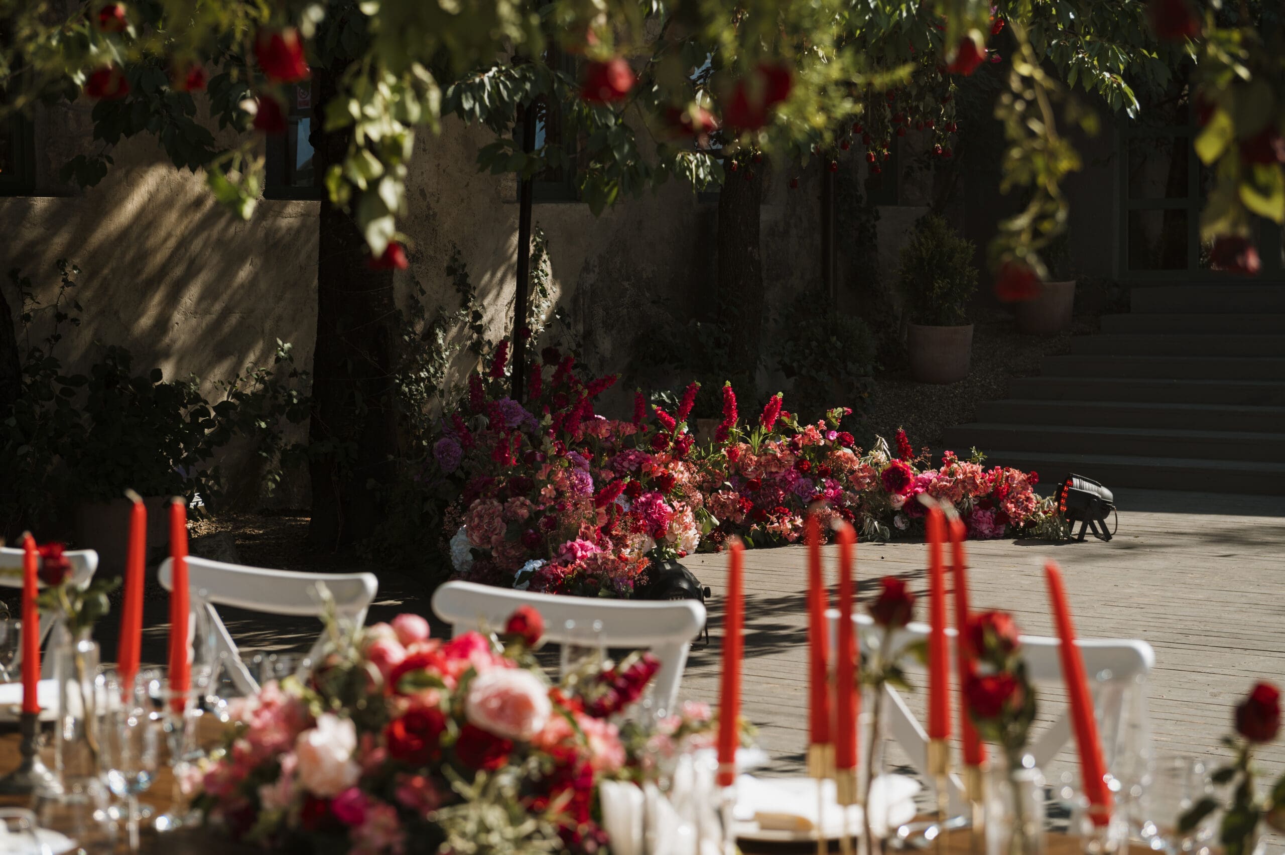 Romantic wedding reception table with red candles and vibrant floral