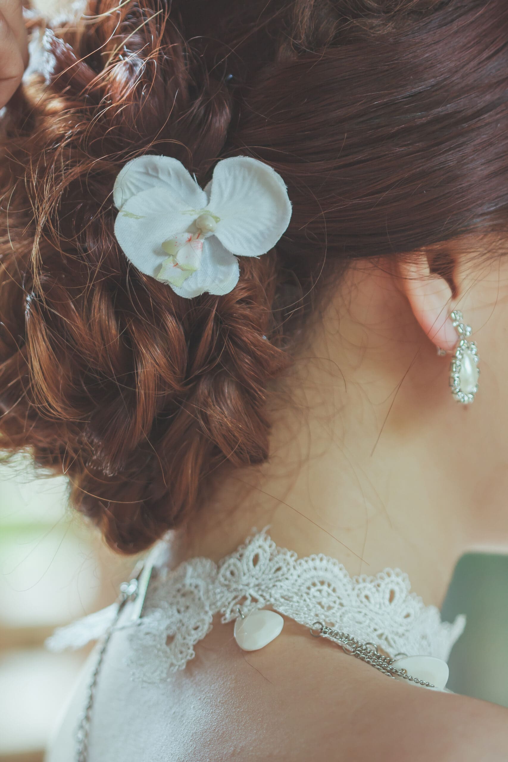 Close-up of a bridal updo featuring a white flower hair pin