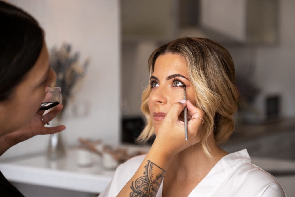 Bride receiving professional eye makeup application before her wedding ceremony